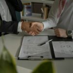deux personnes se serrant la main sur un morceau de papier
