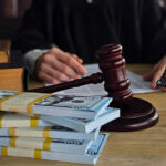 Judge sitting at desk with money and gavel in courtroom during legal proceedings