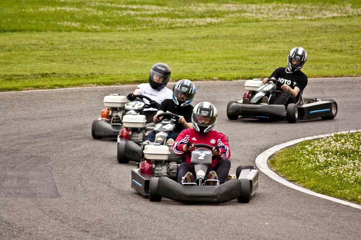 Enfants en karts colorés sur une piste avec virages et herbe environnante