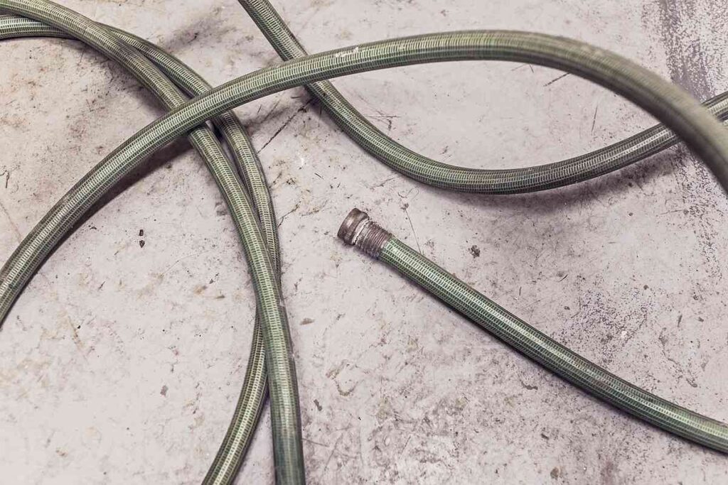 Tuyau vert enroulé sur béton, embout métallique détaché