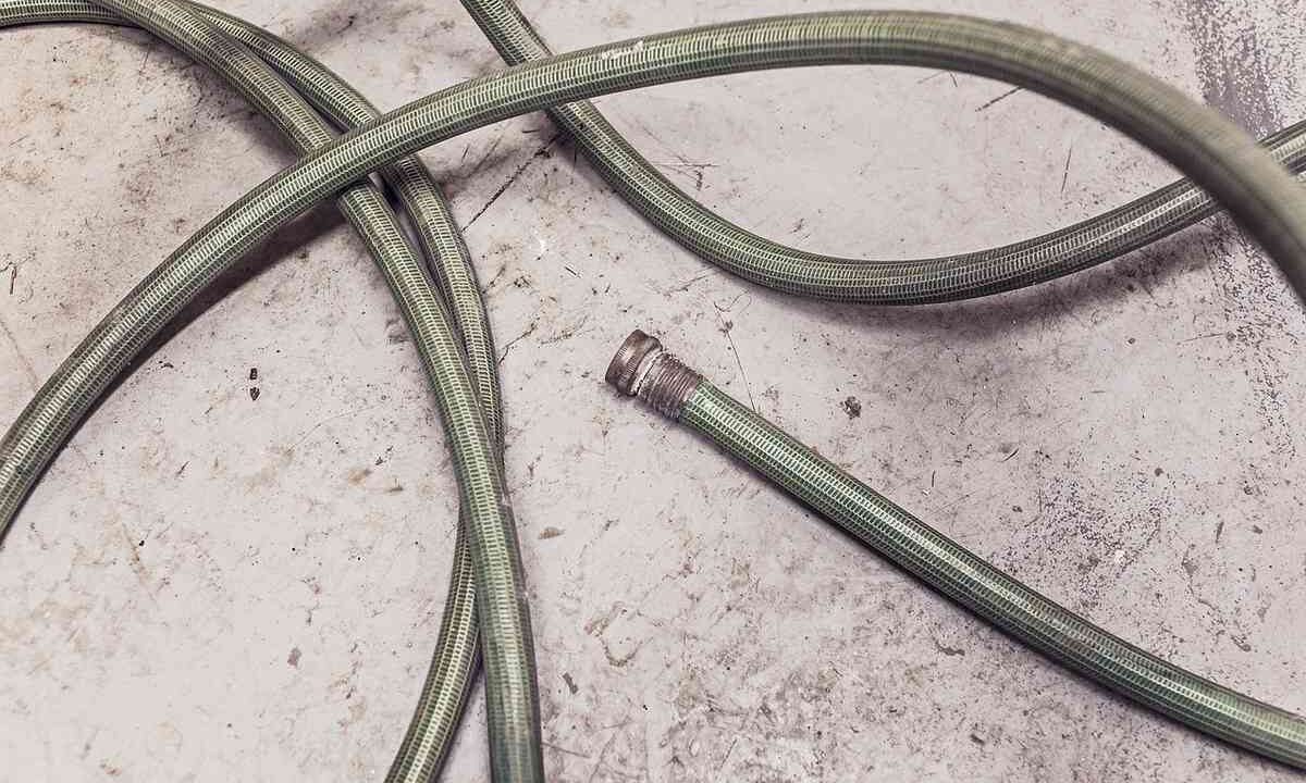 Tuyau vert enroulé sur béton, embout métallique détaché