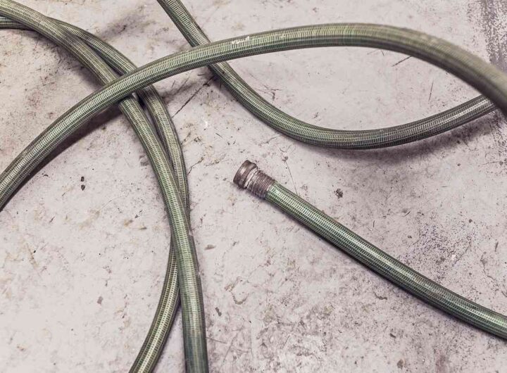 Tuyau vert enroulé sur béton, embout métallique détaché