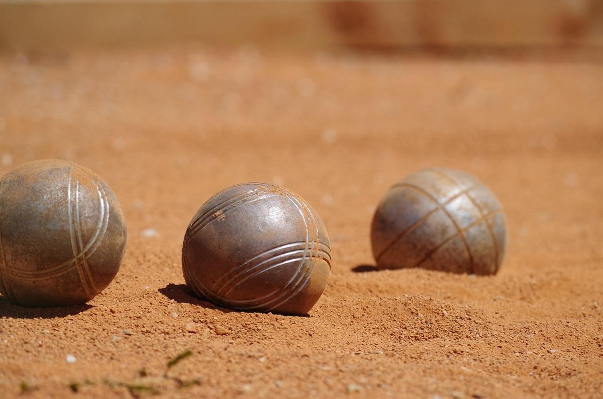 Trois boules de métal reposent sur sable terrain de pétanque Trois boules de métal reposent sur sable terrain de pétanque