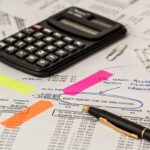 Calculatrice, stylo et feuilles de papier avec post-it