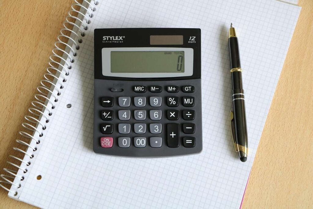 Une calculatrice posée sur un cahier quadrillé à côté d'un stylo