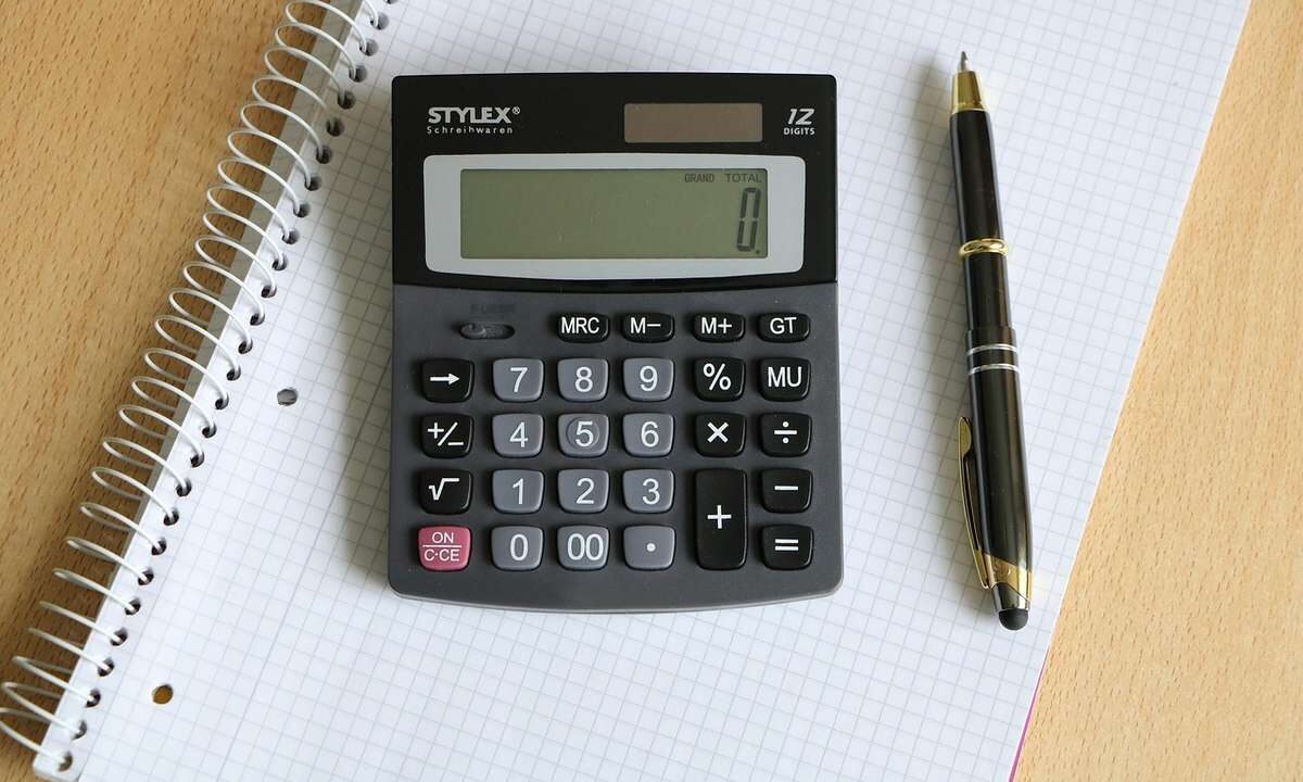 Une calculatrice posée sur un cahier quadrillé à côté d'un stylo