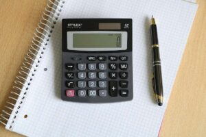 Une calculatrice posée sur un cahier quadrillé à côté d'un stylo