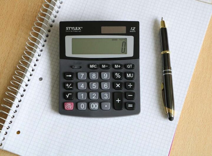 Une calculatrice posée sur un cahier quadrillé à côté d'un stylo