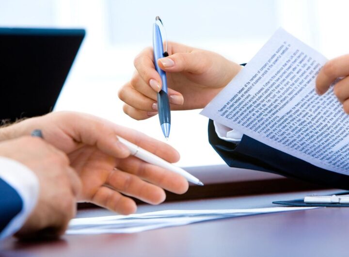 Deux mains échangent un stylo et des papiers sur un bureau